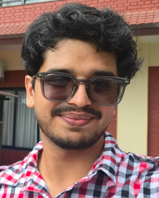 Sushank Ghimire smiling in sunglasses and a red checked shirt